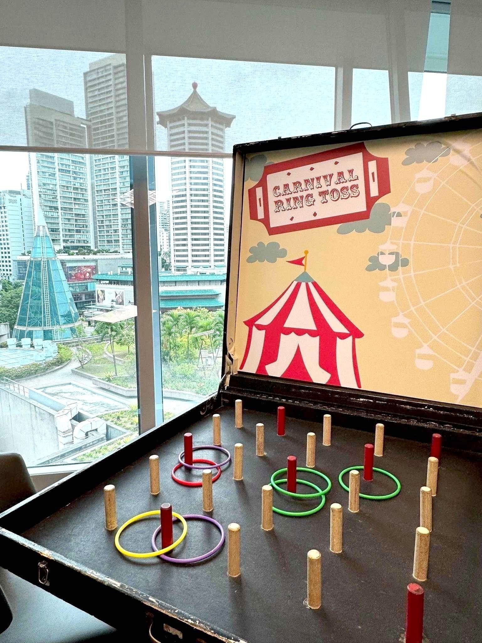Carnival Games Singapore: A Family-Day Stamp Card Plan 3 Carnival ring toss with colourful rings and wooden pegs beside a window