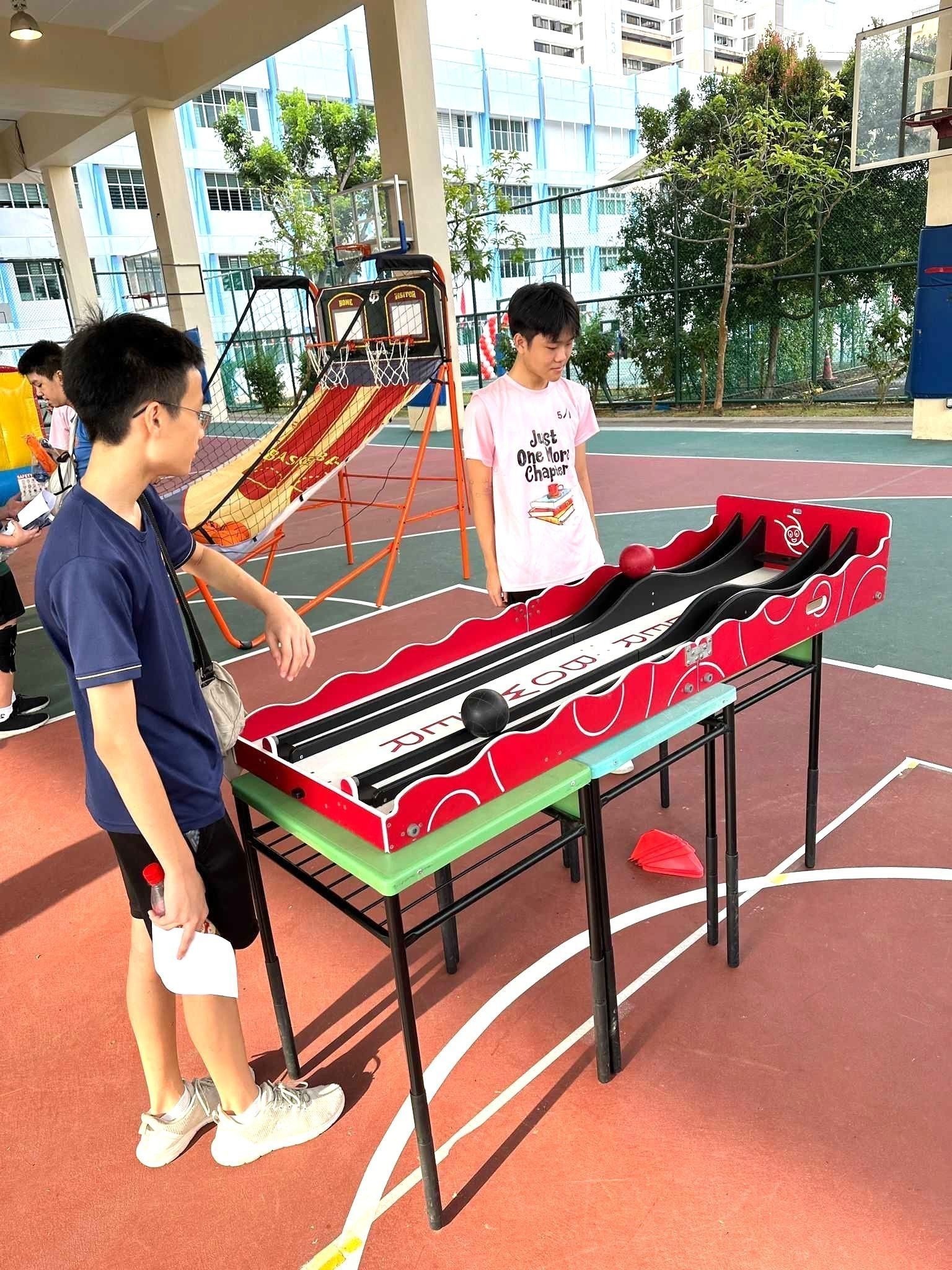 Carnival Games Singapore: A Family-Day Stamp Card Plan 5 Children playing a tabletop bowling carnival game at a covered school event